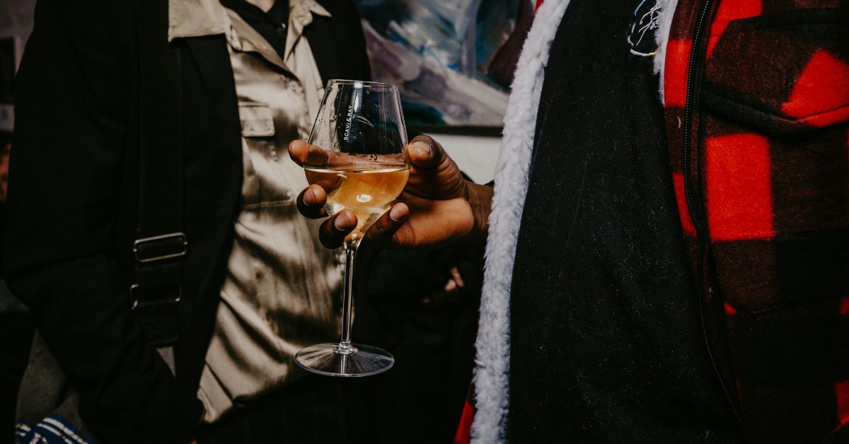 Man holding a glass of white wine by the bowl of the glass
